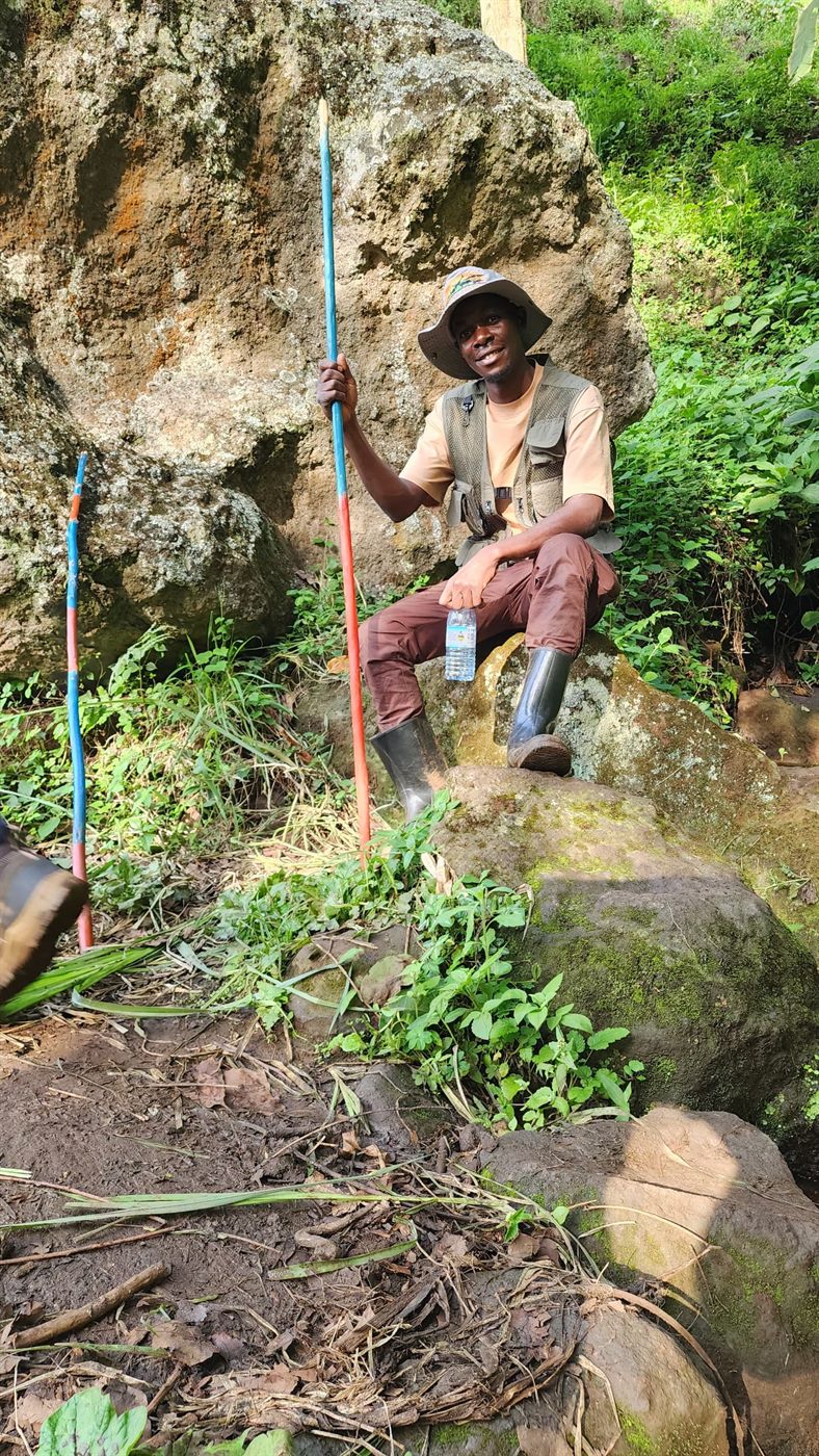 Paius seated on rocks during a forest trail