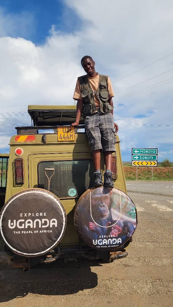 Paius standing on a safari vehicle with Explore Uganda spare tire covers