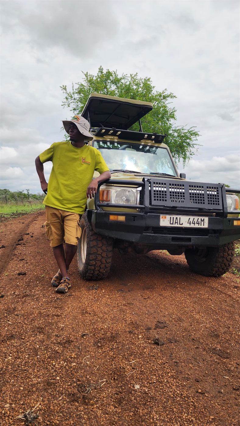 Paius leaning on a safari vehicle