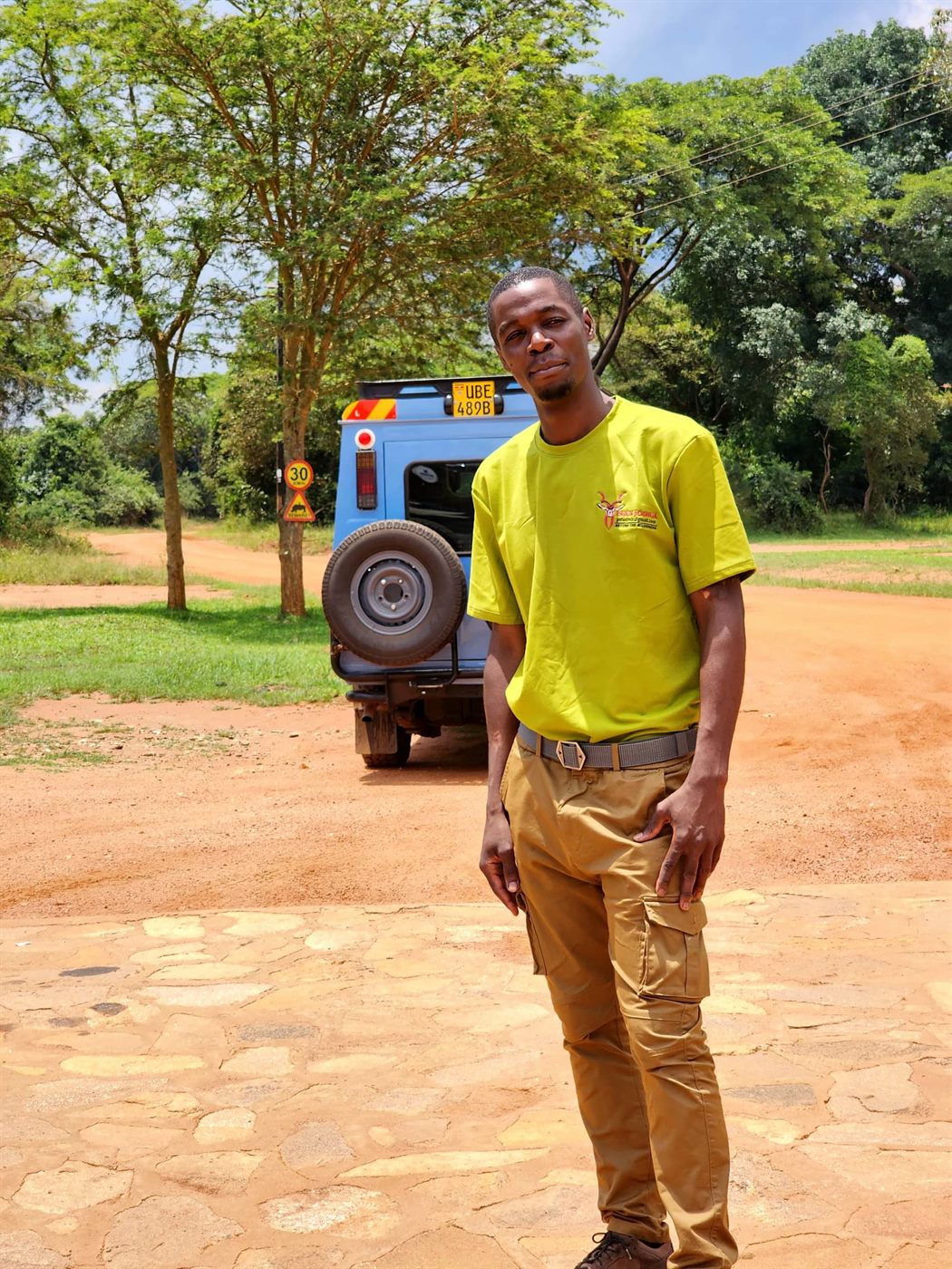 Paius beside a safari vehicle on a park road