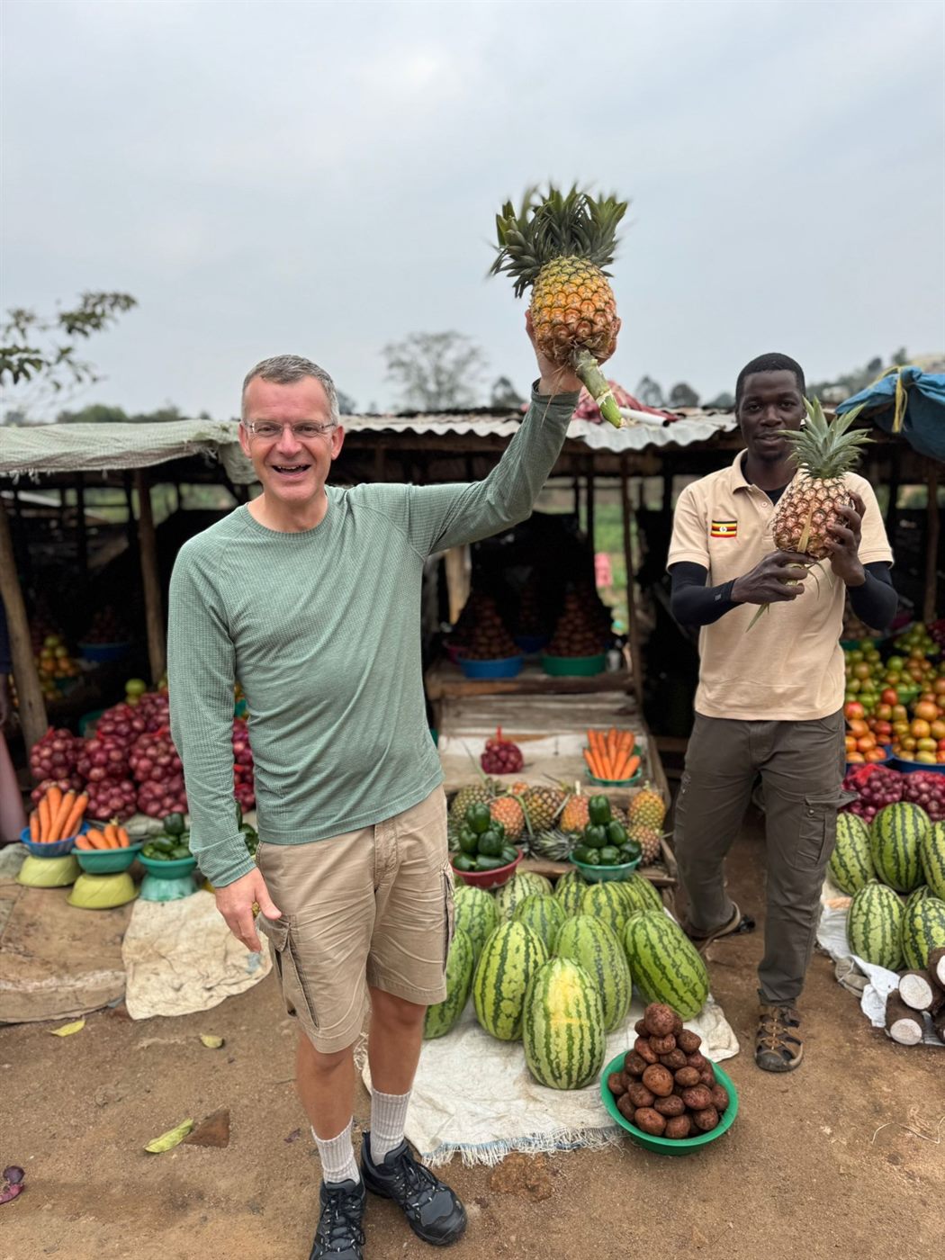 Paius and a guest holding pineapples at a market