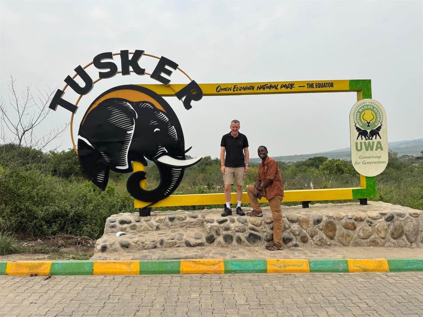 Paius and a guest at Queen Elizabeth National Park equator sign